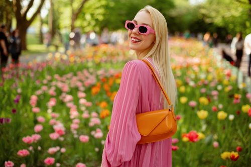 Fashionable young woman in pink dress with orange purse and sunglasses