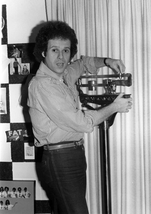 Richard Simmons posing with a scale in 1980