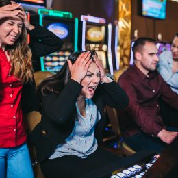 A group of friends playing slot machines with angry expressions after losing