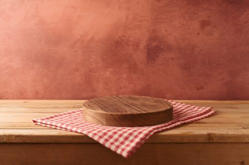 Empty podium on wooden table with tablecloth over rustic terra cotta-colored wall background