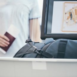 Airport security check. Young man holding passport and waiting for x-ray control his luggage.