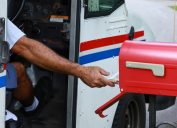 Mail man reaches out of his truck to deliver mail. Official mail delivery slowdown started on October 1, 2021, as seen on October 2, 2021.
