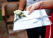 White wedding envelope with a boutonniere in the hand of a woman.