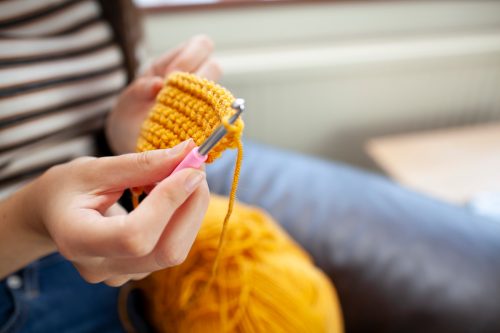 Close-up of woman crocheting with yellow wool
