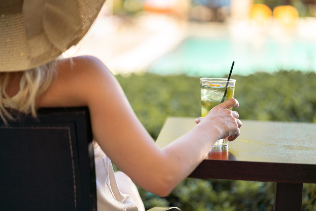 A closeup of a woman drinking a cocktail or beverage on her front porch
