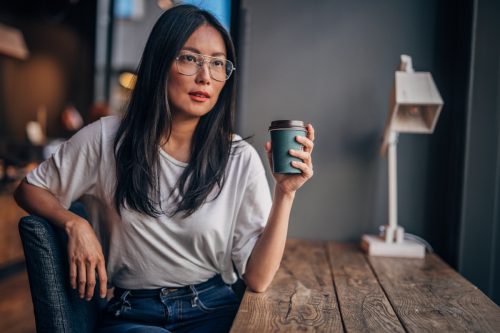 woman with eyeglasses drinking take out coffee.