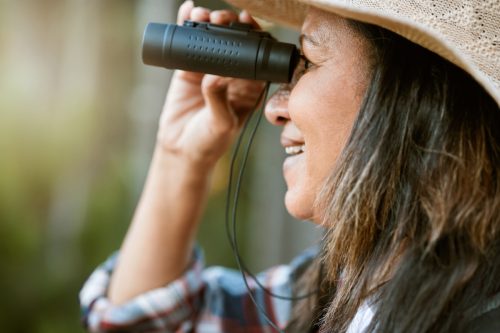 Close up of mature woman looking through binoculars outside