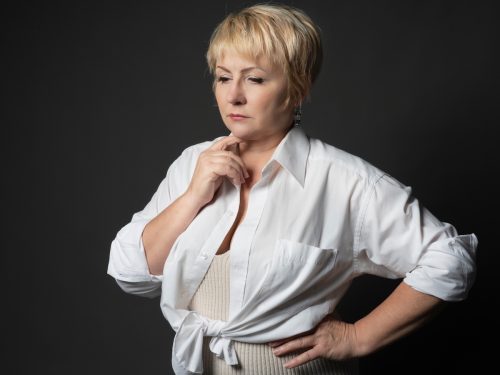 Portrait of a thoughtful adult woman with short blonde hair in a stylish white shirt . 
