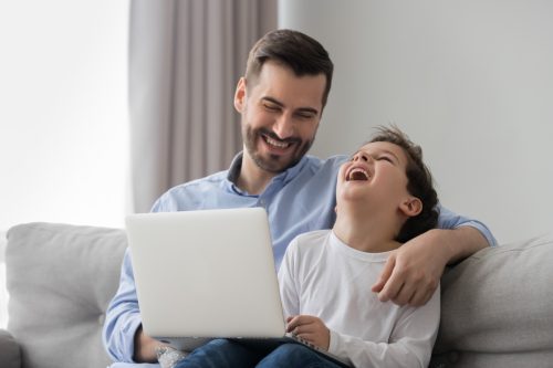 father and son laughing as they read "would you rather" questions off the computer