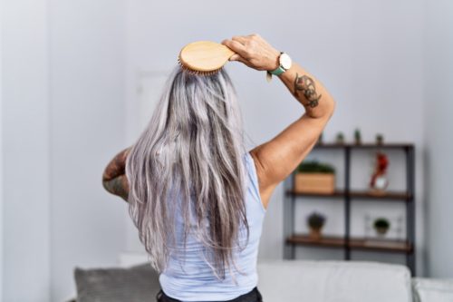 Middle Aged Woman Brushing Her Long Gray Hair