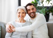 family, generation and people concept - happy smiling senior mother with adult son hugging at home