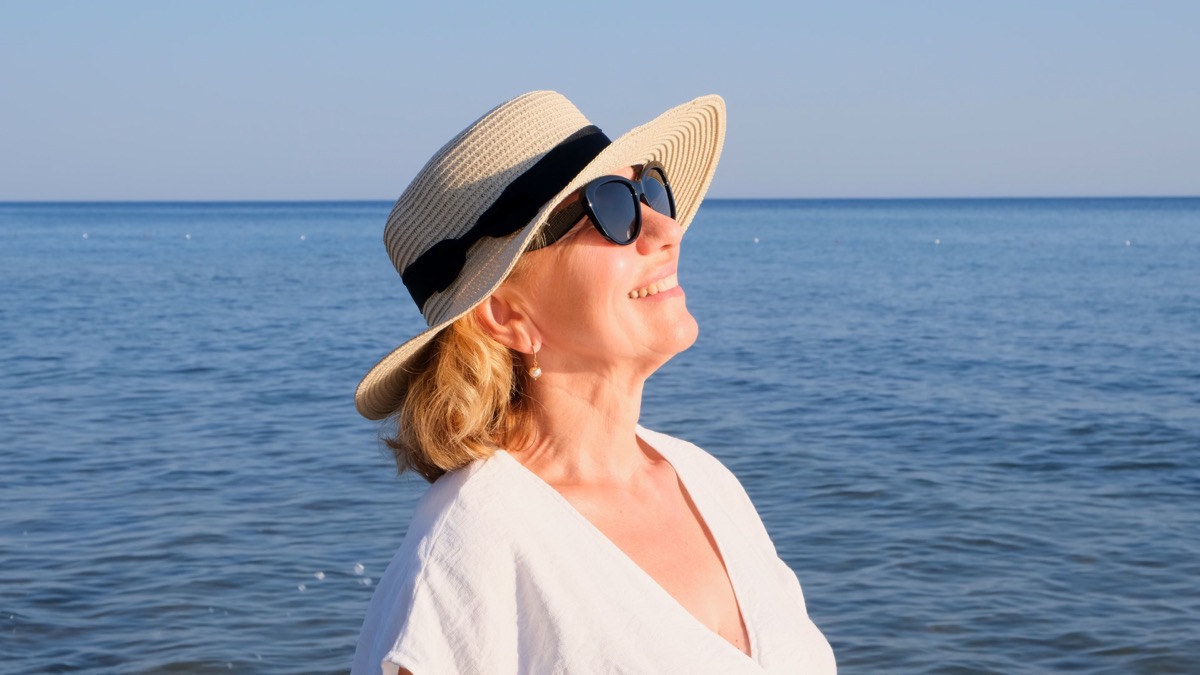 Older Woman by the Water with Hat and Sunglasses on