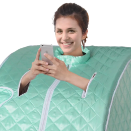 A woman using a portable sauna while smiling and looking at her phone