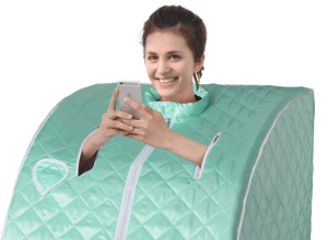 A woman using a portable sauna while smiling and looking at her phone