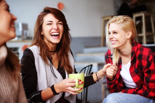 Three women laughing together at coffee shop
