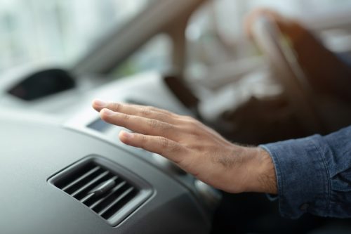 Closeup of hand driver man checking adjusting air from conditioning the cooling system with flow of cold air in car. 