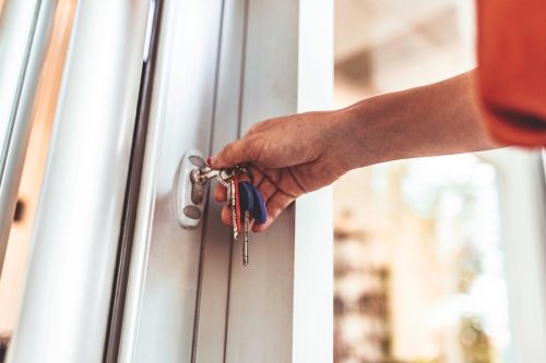 woman unlocking front door of home with keys