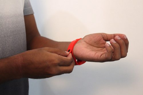 Close up of a man putting on a red silicone wristband