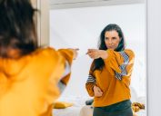Self confident woman pointing finger at her reflection in mirror