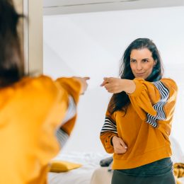 Self confident woman pointing finger at her reflection in mirror