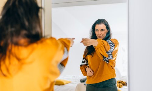 Self confident woman pointing finger at her reflection in mirror