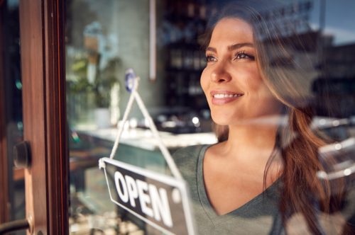Woman looking proud as she flips the "open sign" on her new business