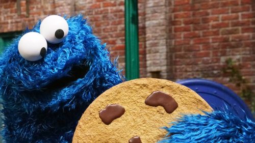 cookie monster holding a big chocolate chip cookie