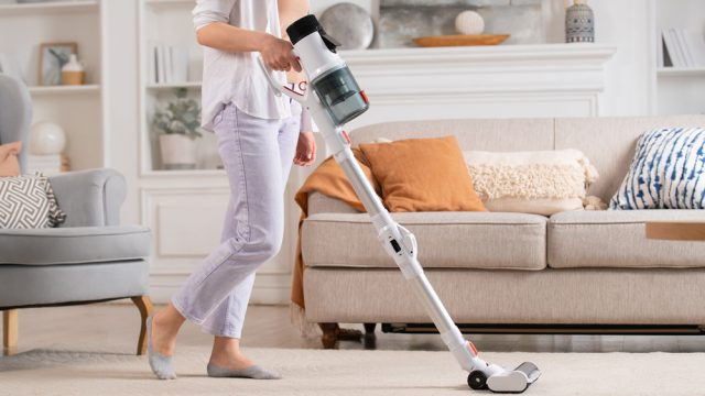A person using a cordless vacuum in their living room