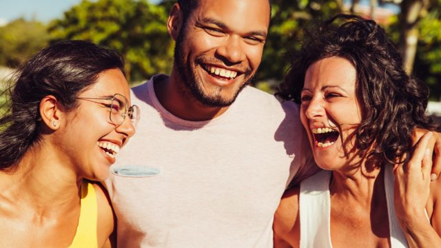 Man and two women laughing out in the sun