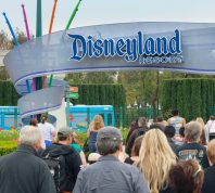 A crowd of people walking in through the entrance to Disneyland park