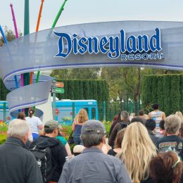 A crowd of people walking in through the entrance to Disneyland park