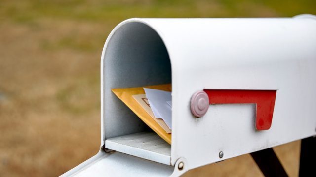 Close up of a mailbox opened with the contents of the mailbox showing with shallow depth of field