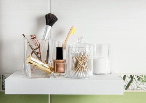 Make up products organizing in bathroom concept. Beauty products in organizer container box on tidy way on minimalist shelf. Cotton pads stacked, Q-tips and make up brushes.