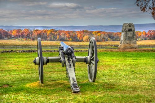 A cannon in the foreground with the fall foliage of Gettysburg, Pennsylvania in the background