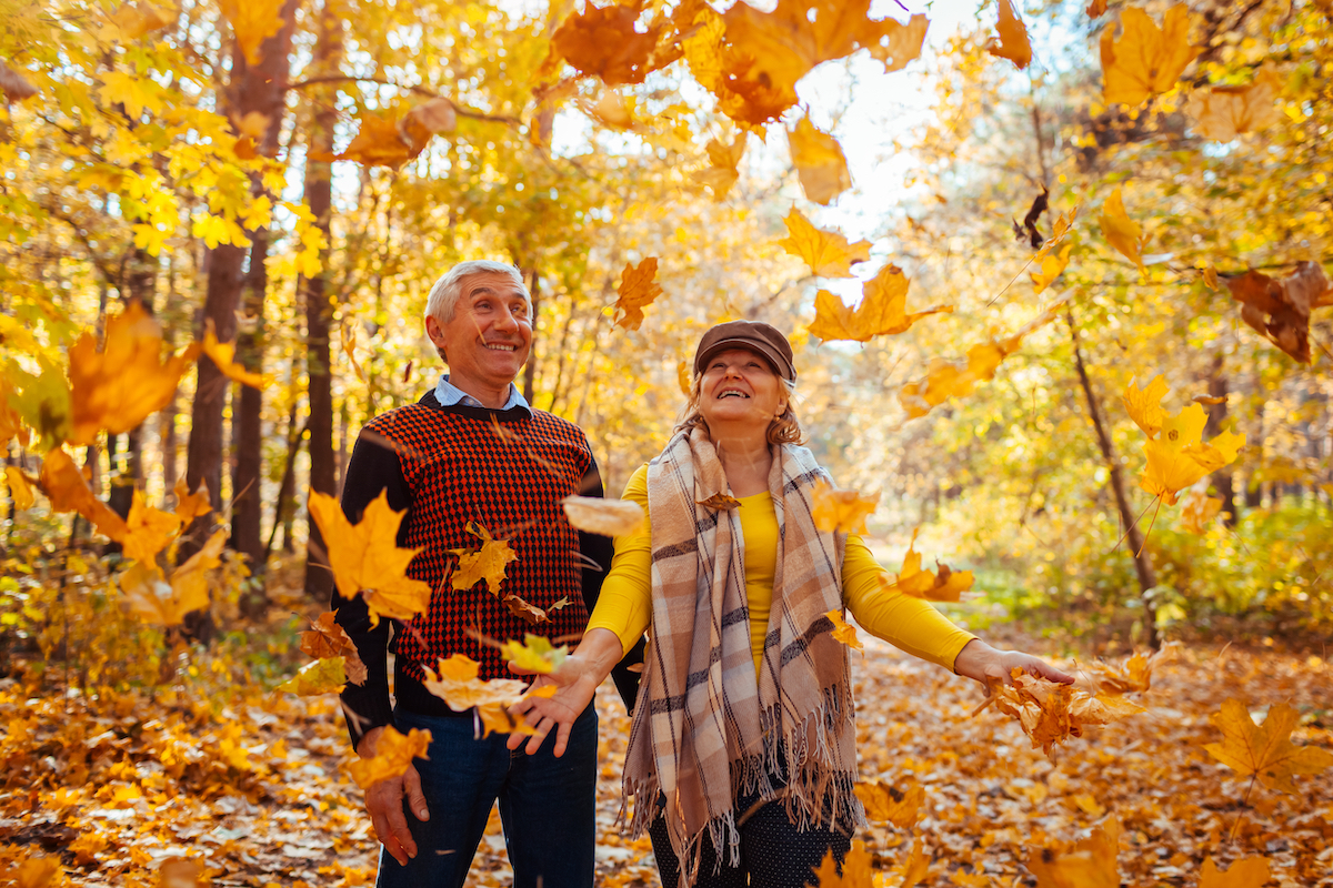 Happy senior couple throwing leaves on a fall day