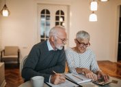 A happy senior couple calculating their finances in a beautiful home.