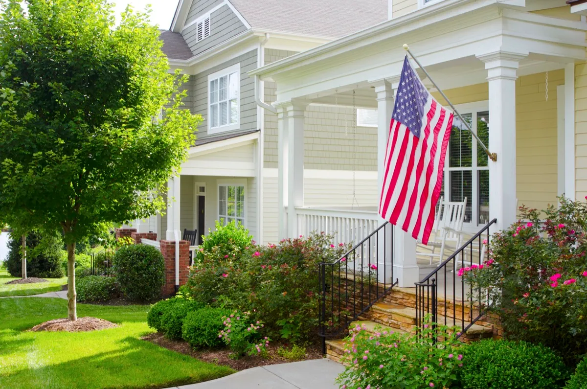Detail of a bungalow/cottage-style front porch with an American Flag hanging from the front column.