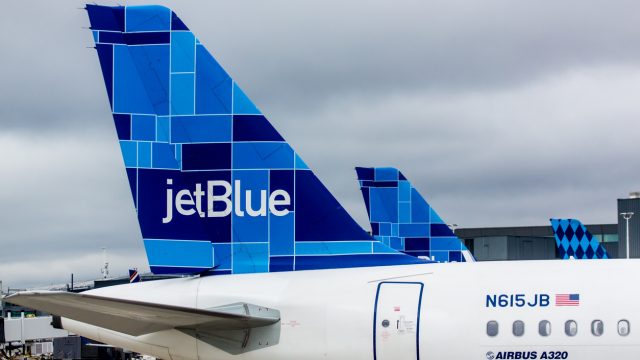A close up of a JetBlue plane's tail fin while parked at an airport