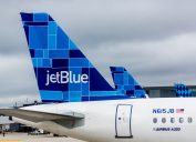 A close up of a JetBlue plane's tail fin while parked at an airport