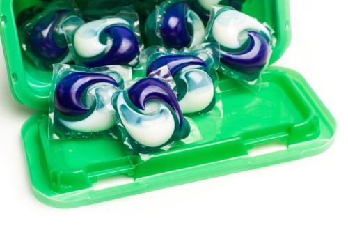Detergent pods in a green plastic box on a white background