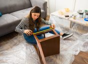 woman measuring a chair while working on a furniture flipping project at home