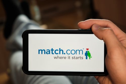 Match com logo on the screen of mobile phone in man's hand. 
