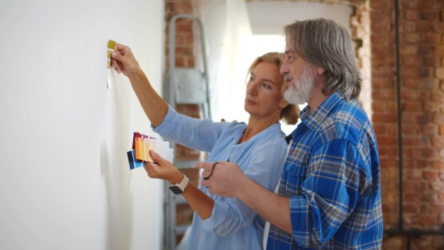 Mature couple looking at paint swatches up against wall.