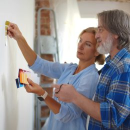 Mature couple looking at paint swatches up against wall.