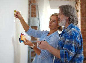 Mature couple looking at paint swatches up against wall.