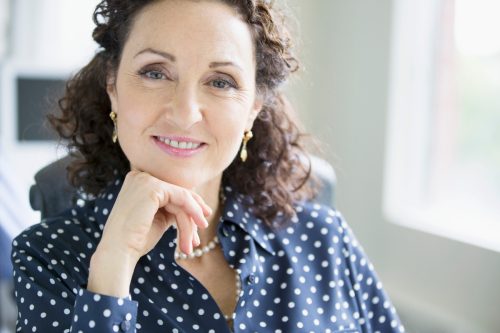 portrait of pretty, middle-aged woman at office wearing a navy blue and white polka dot blouse