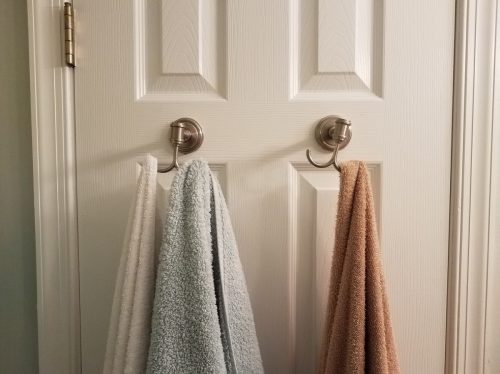 used towels hanging on hooks on white bathroom door