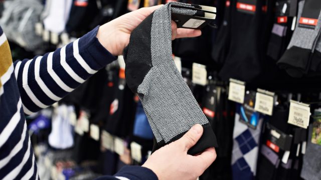 Close up of a person picking out a pair of socks in a store.