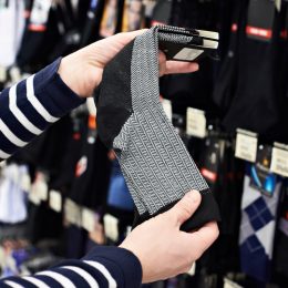 Close up of a person picking out a pair of socks in a store.