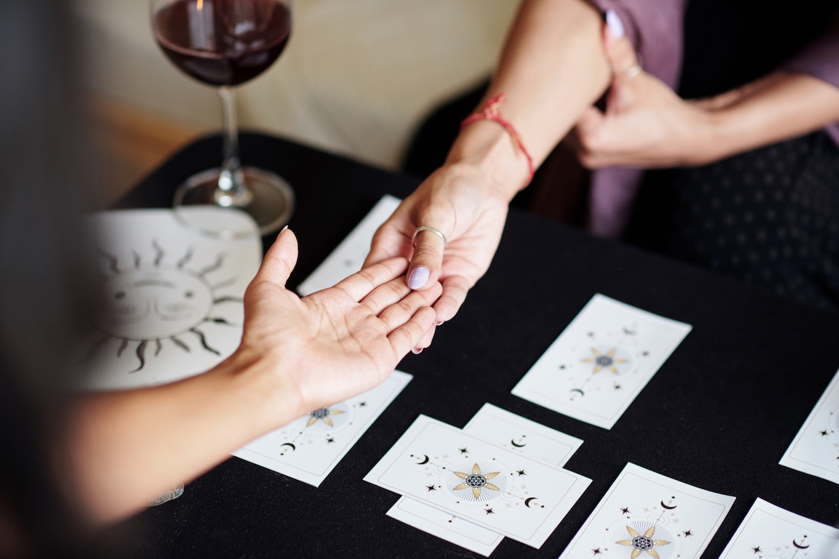 Fortune teller asking young woman to give her hand for palm reading
